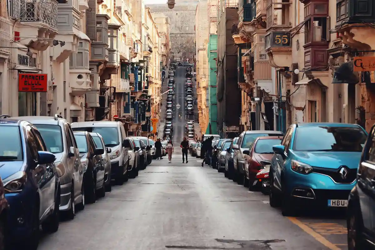 Calle estrecha con coches aparcados en La Valeta, Malta — ejemplo típico del tráfico y estacionamiento en la isla.