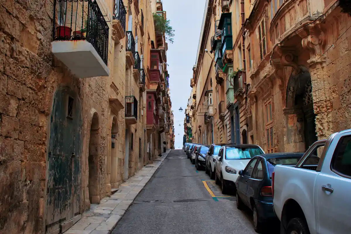 Calle estrecha en Valletta con coches aparcados, donde muchos conductores en Malta reciben multas por estacionamiento.