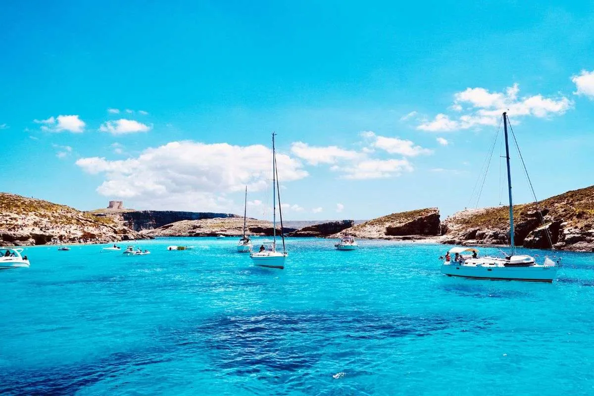 Laguna Azul en Comino, Malta, con barcos turísticos anclados y agua turquesa durante la temporada alta