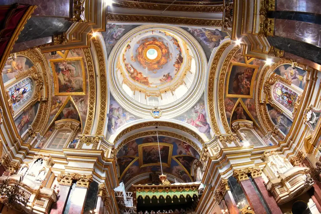 Vista hacia la cúpula y las bóvedas de St. John’s Co-Cathedral en La Valeta, con pinturas barrocas, marcos dorados y una composición arquitectónica diseñada para impresionar al visitante.