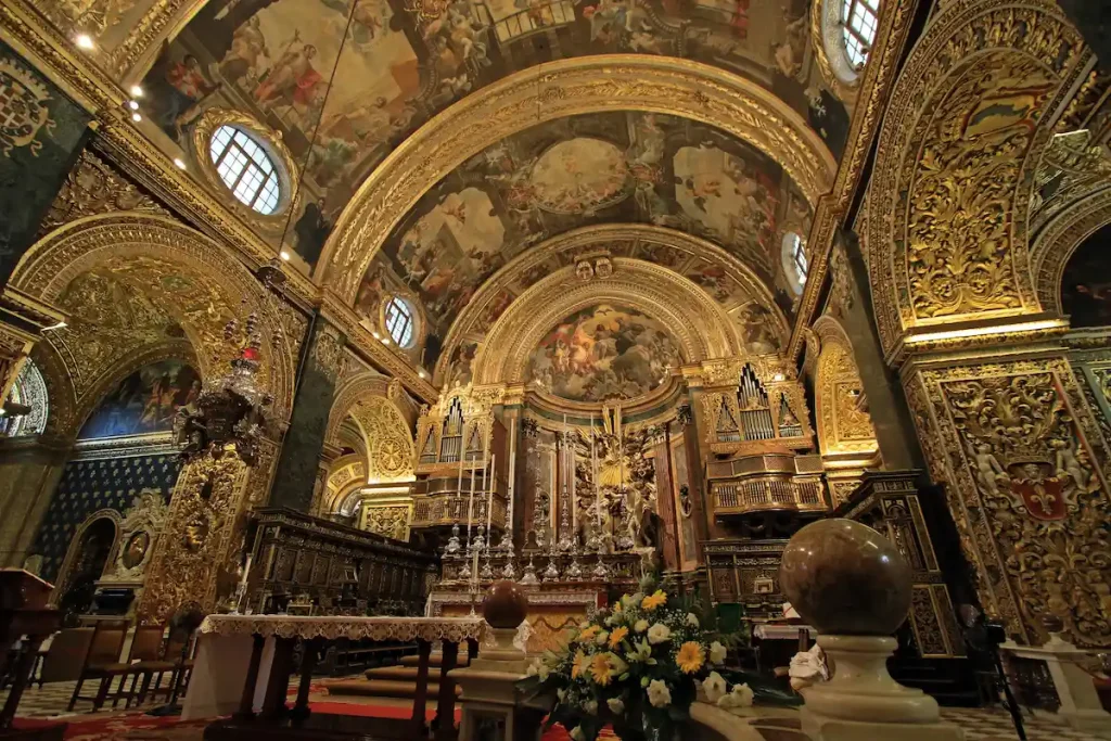 Interior barroco de St. John’s Co-Cathedral en La Valeta, con bóvedas doradas, frescos monumentales y decoración opulenta que cubre todo el espacio del templo.
