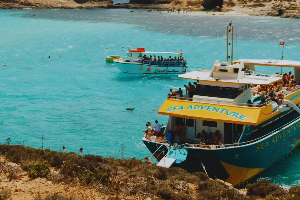 Barco de excursión fondeado en Blue Lagoon, Comino (Malta), durante la temporada alta de verano