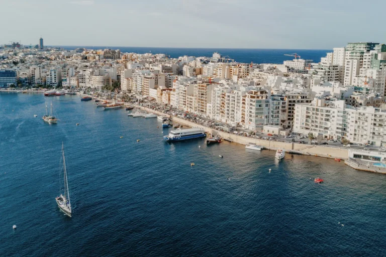 Vista aérea del paseo marítimo de Sliema con ferris, barcos y edificios urbanos en Malta