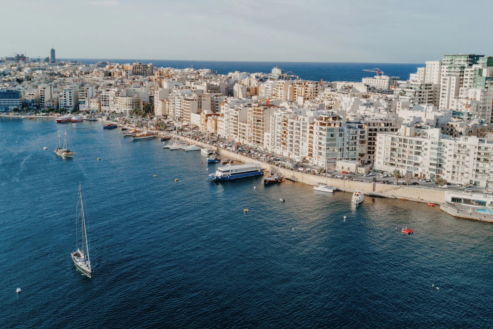 Vista aérea del paseo marítimo de Sliema con ferris, barcos y edificios urbanos en Malta