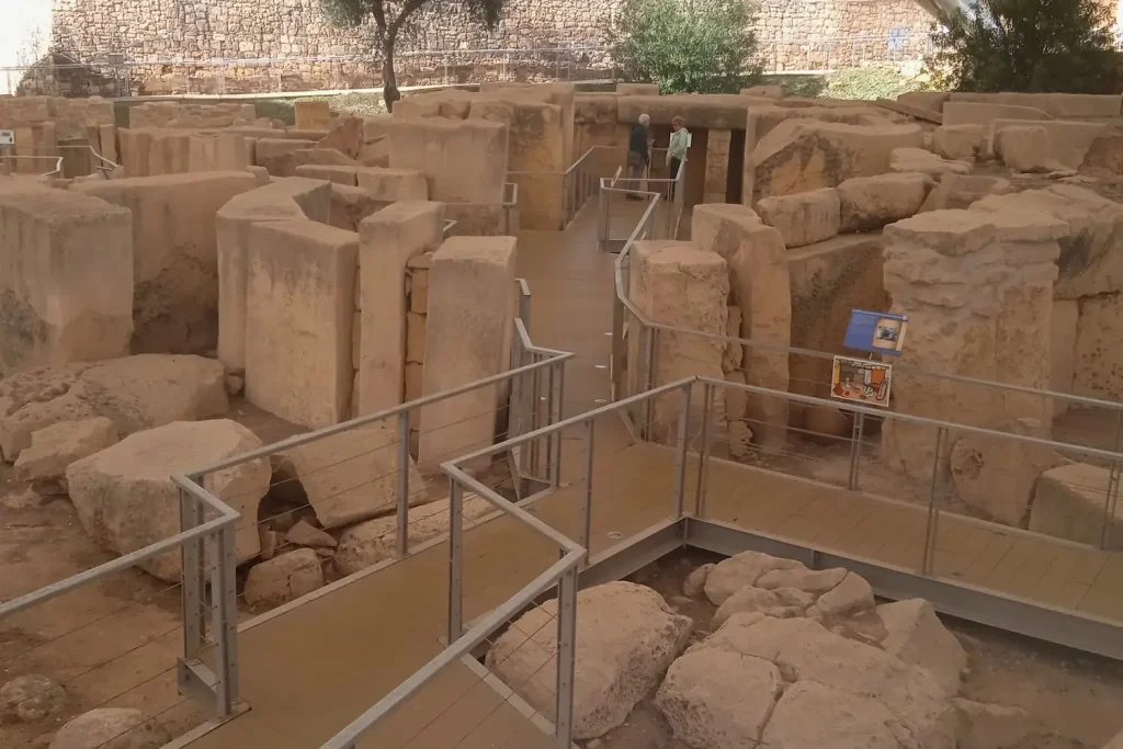 Bloques megalíticos de piedra y el pasillo del templo de Tarxien en Malta con una pasarela moderna para visitantes.