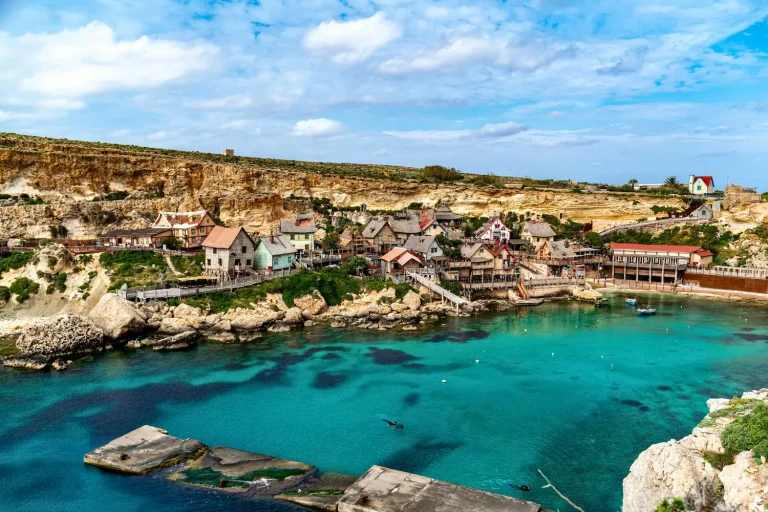 Popeye Village en Anchor Bay, Malta, con sus coloridas casas de película junto al mar turquesa y acantilados rocosos del norte de la isla.